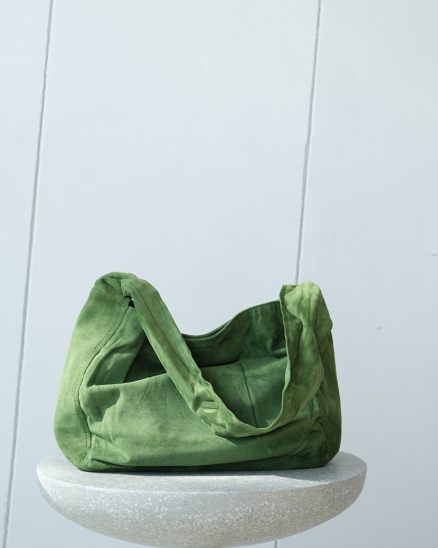 a green suede bag sits on a stool