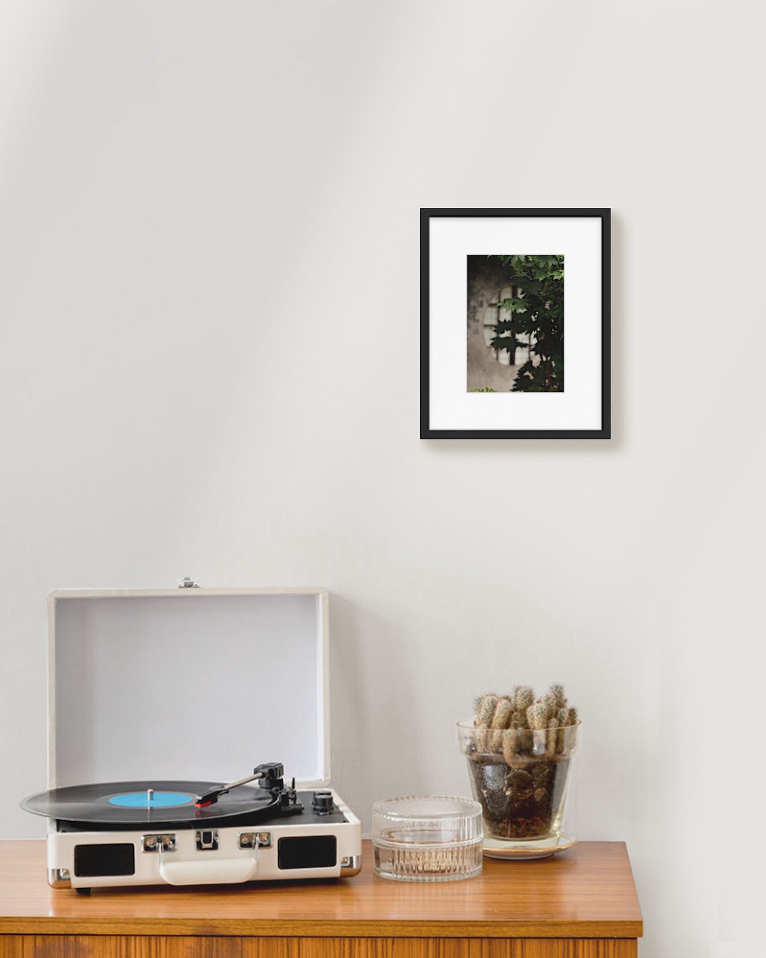 Turntable on a wooden table with a framed picture on the wall