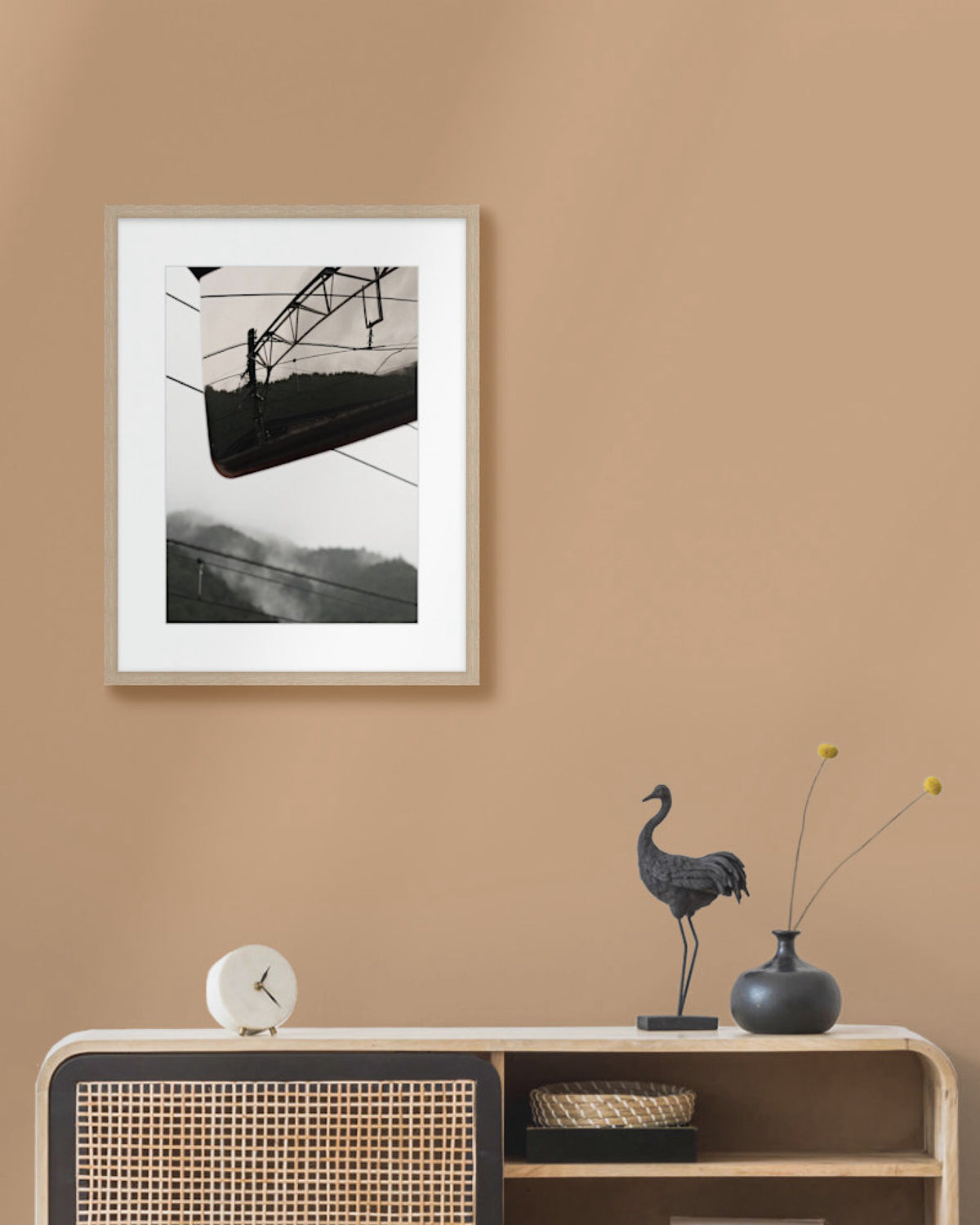 Framed landscape photograph on a beige wall above a wooden console table with decorative items.
