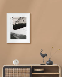 Framed landscape photograph on a beige wall above a wooden console table with decorative items.