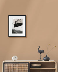 Framed japanese landscape photograph on a beige wall above a wooden console table with decorative items.