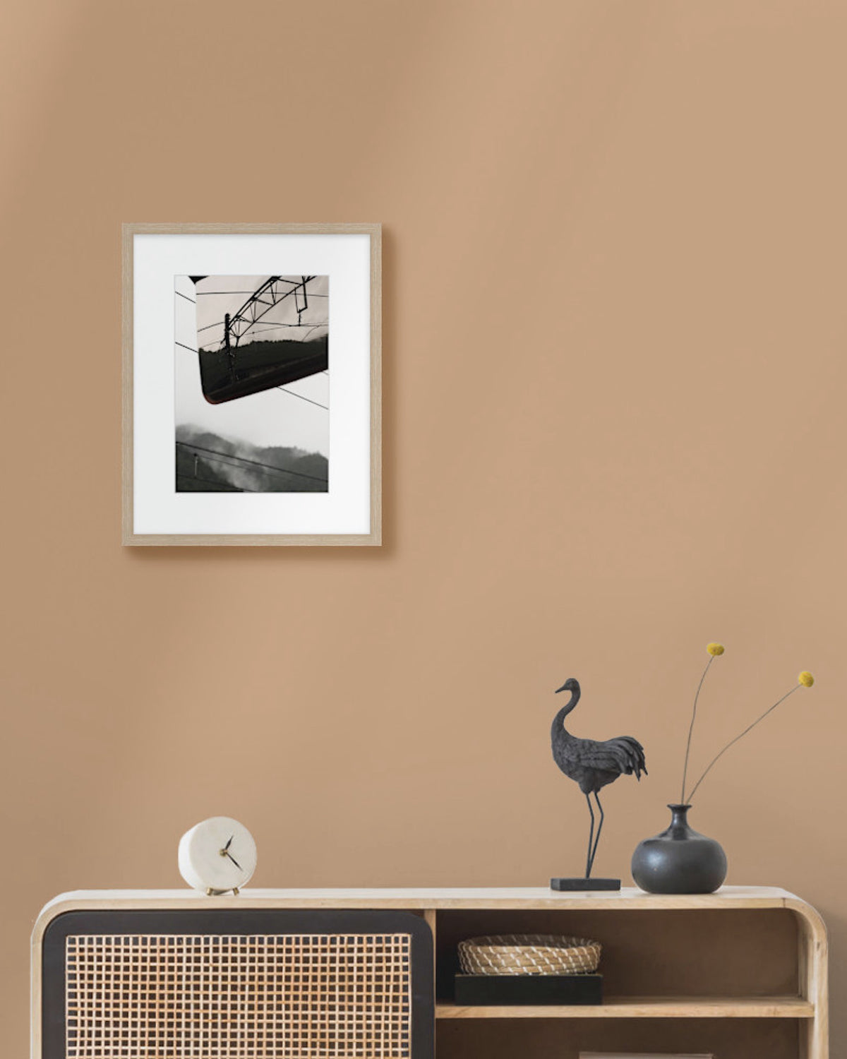 Framed landscape photograph on a beige wall above a wooden console table with decorative items.