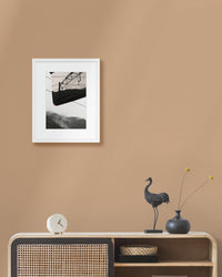 Framed landscape photograph on a beige wall above a wooden console table with decorative items.