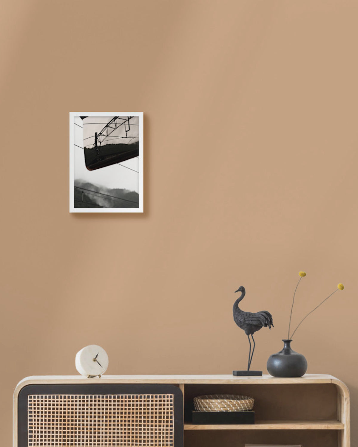 Framed artwork on a beige wall above a wooden console table with decorative items.