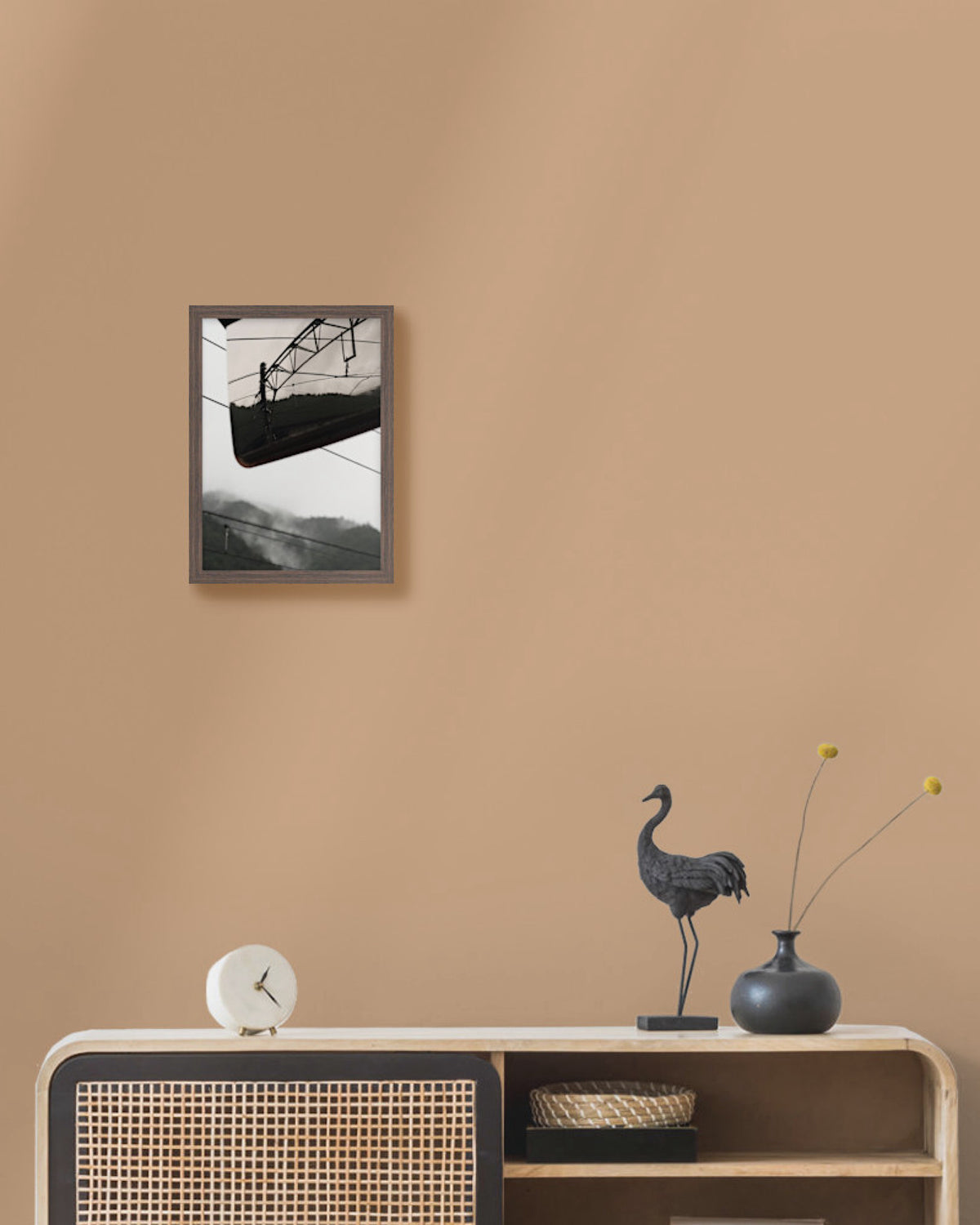 Framed artwork on a beige wall above a wooden console table with decorative items.