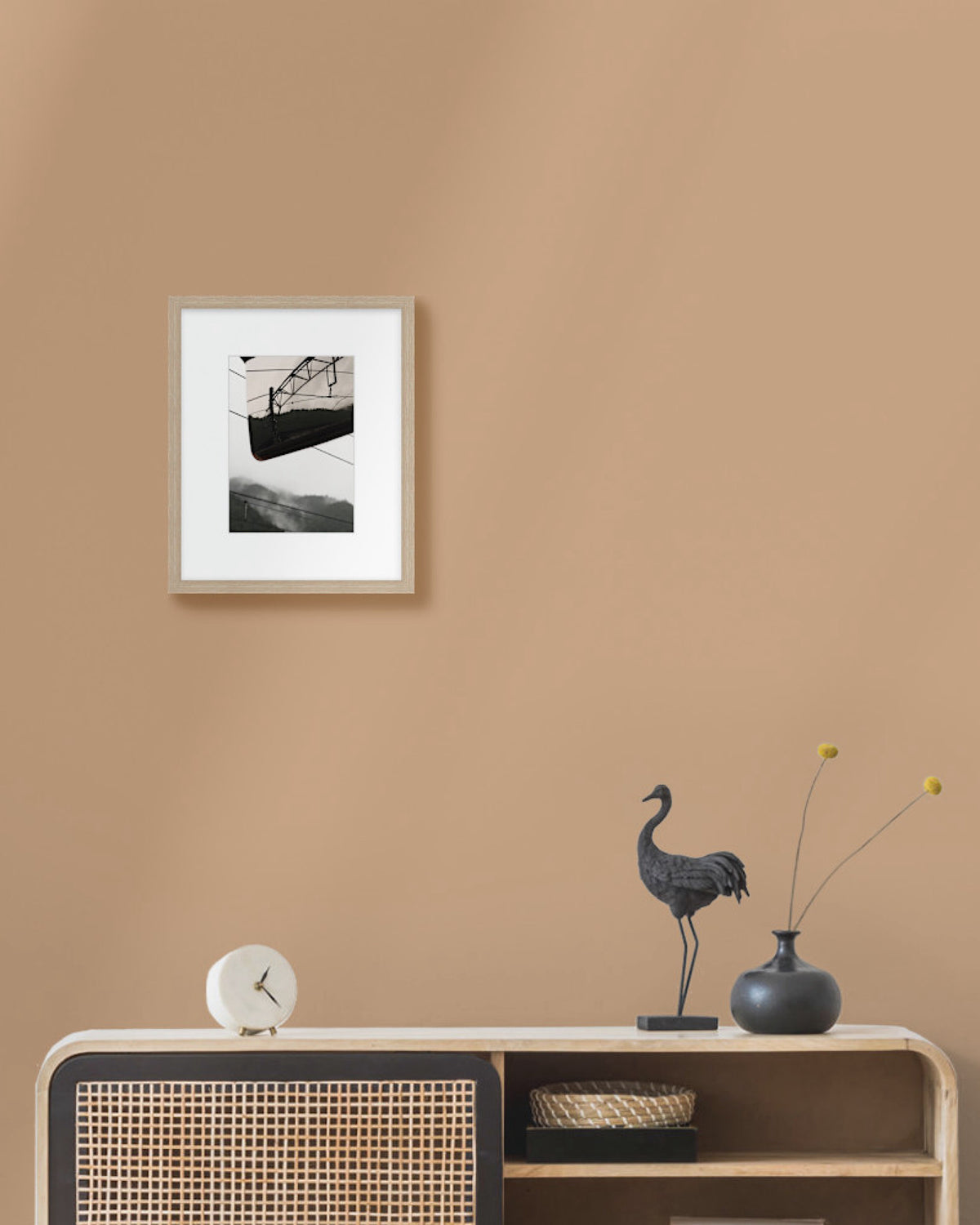 Framed japanese landscape photo on a beige wall above a wooden console table with decorative items.