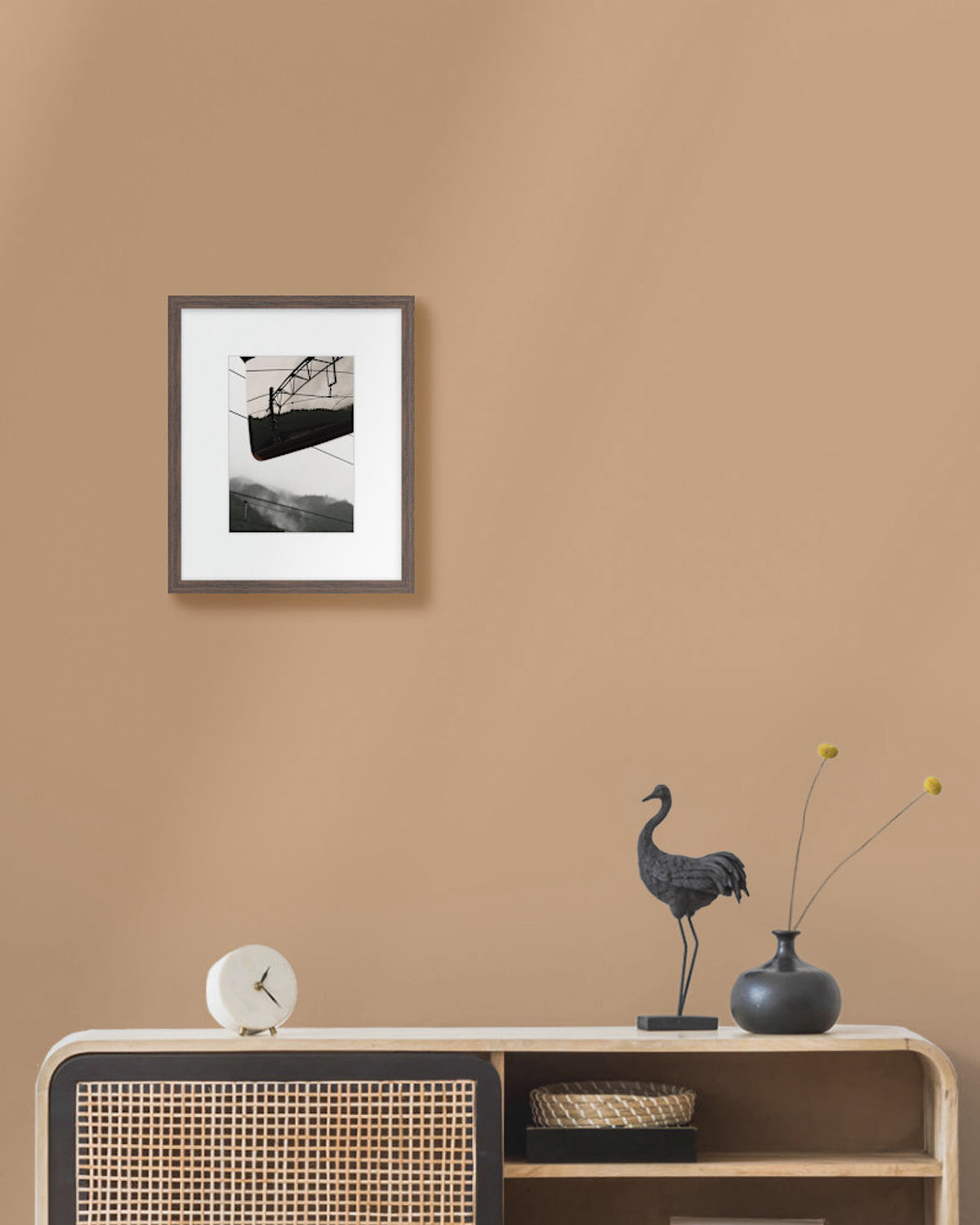 Framed japanese landscape photo on a beige wall above a wooden console table with decorative items.