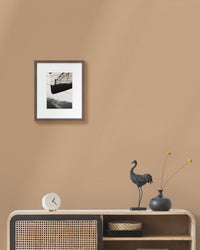 Framed japanese landscape photo on a beige wall above a wooden console table with decorative items.
