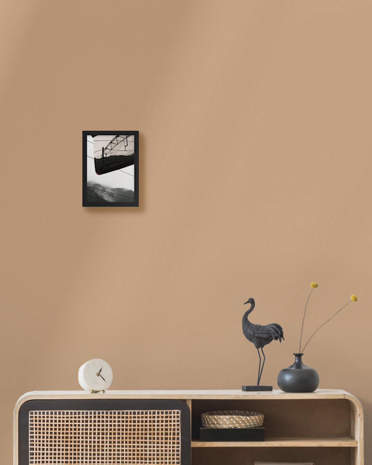 Framed japan black and white photograph on a beige wall above a wooden console table with decorative items.