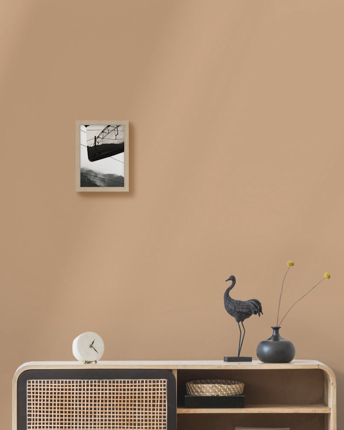 Framed artwork on a beige wall above a console table with decorative items.