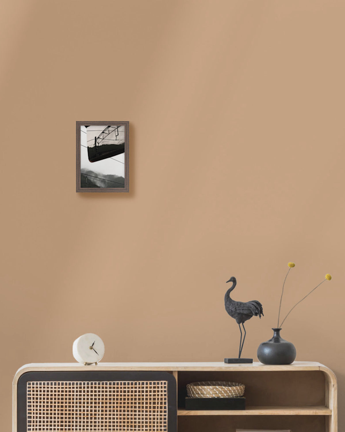 Framed japan landscape fine art print on a beige wall above a wooden console table with decorative items.