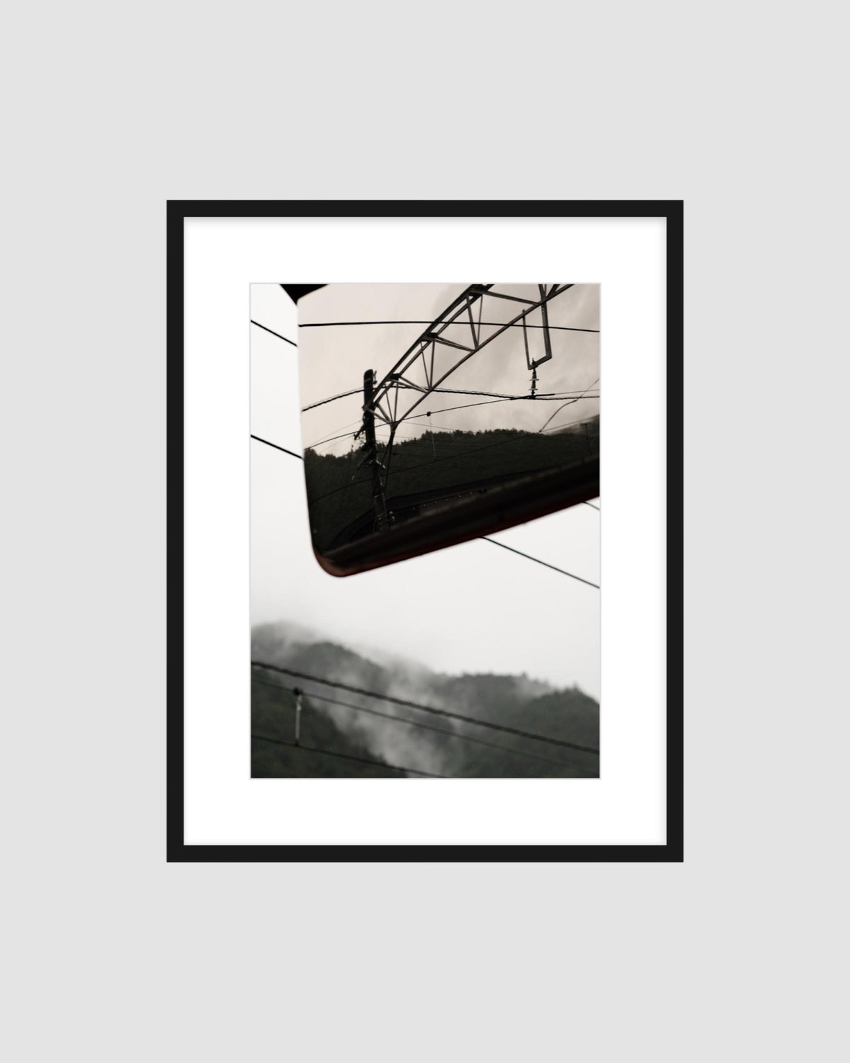 Framed japanese landscape photograph of a mountain and railway against grey sky.