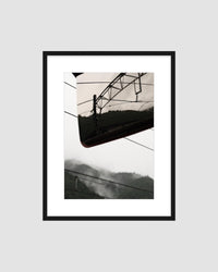 Framed japanese landscape photograph of a mountain and railway against grey sky.