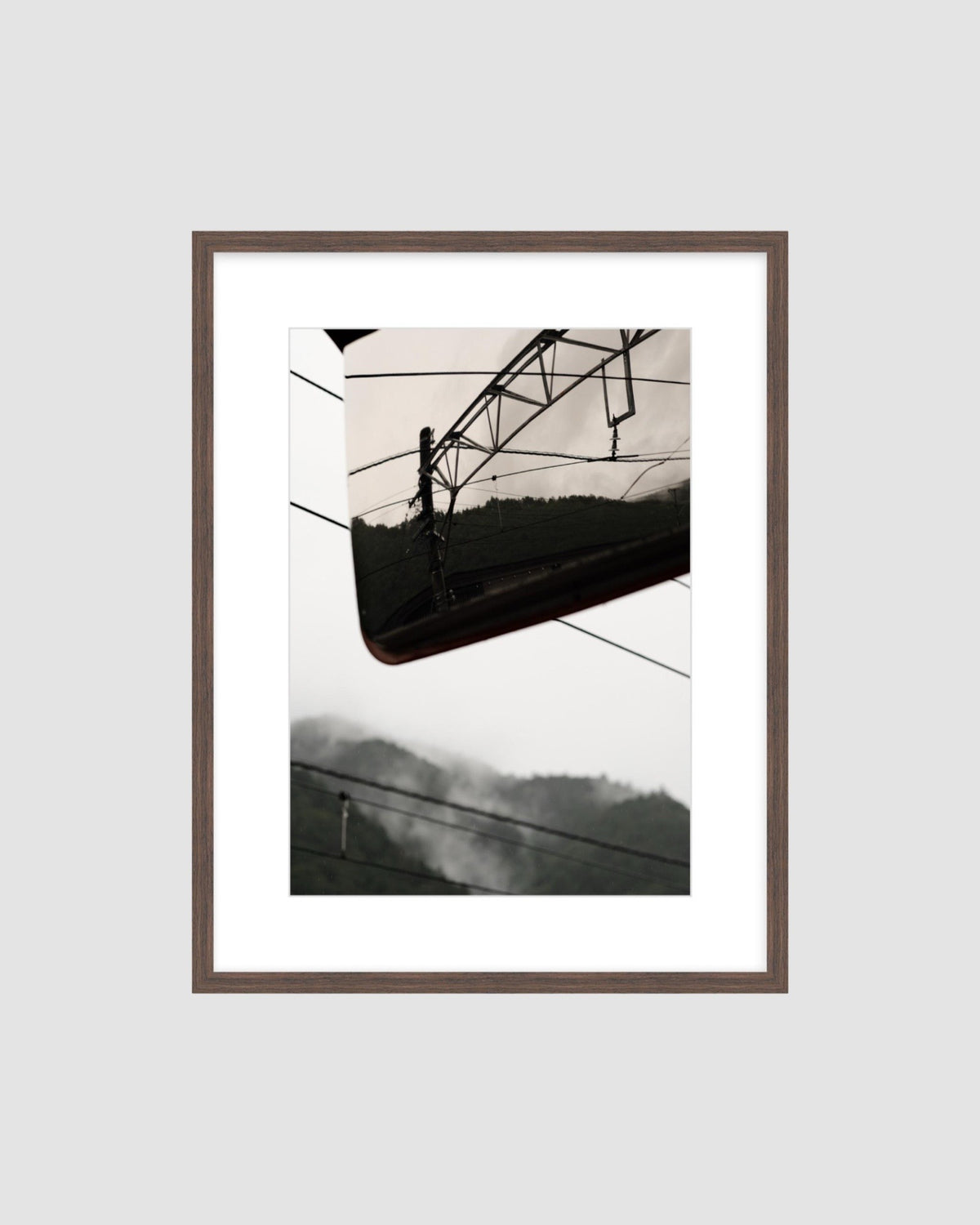 Framed  photograph of a power line and mountains against a light gray background