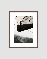 Framed  photograph of a power line and mountains against a light gray background