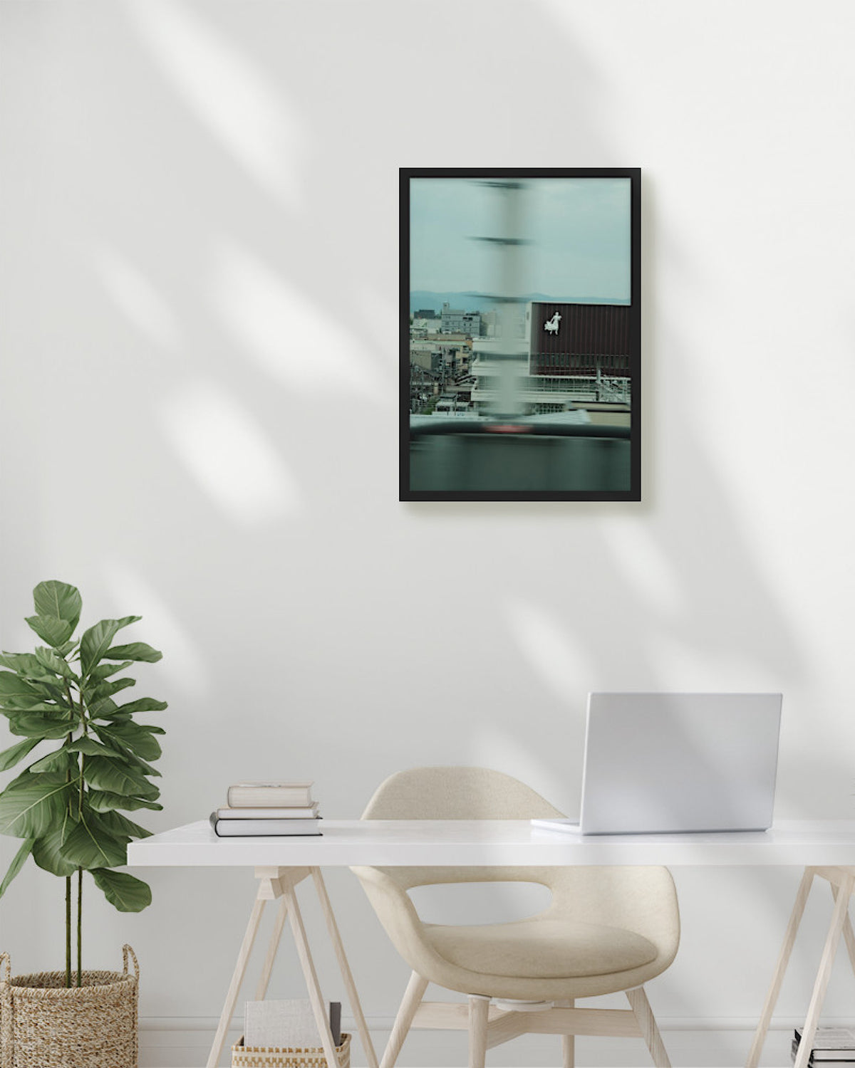 Modern office setup with a framed artwork on the wall, desk, chair, and plant.