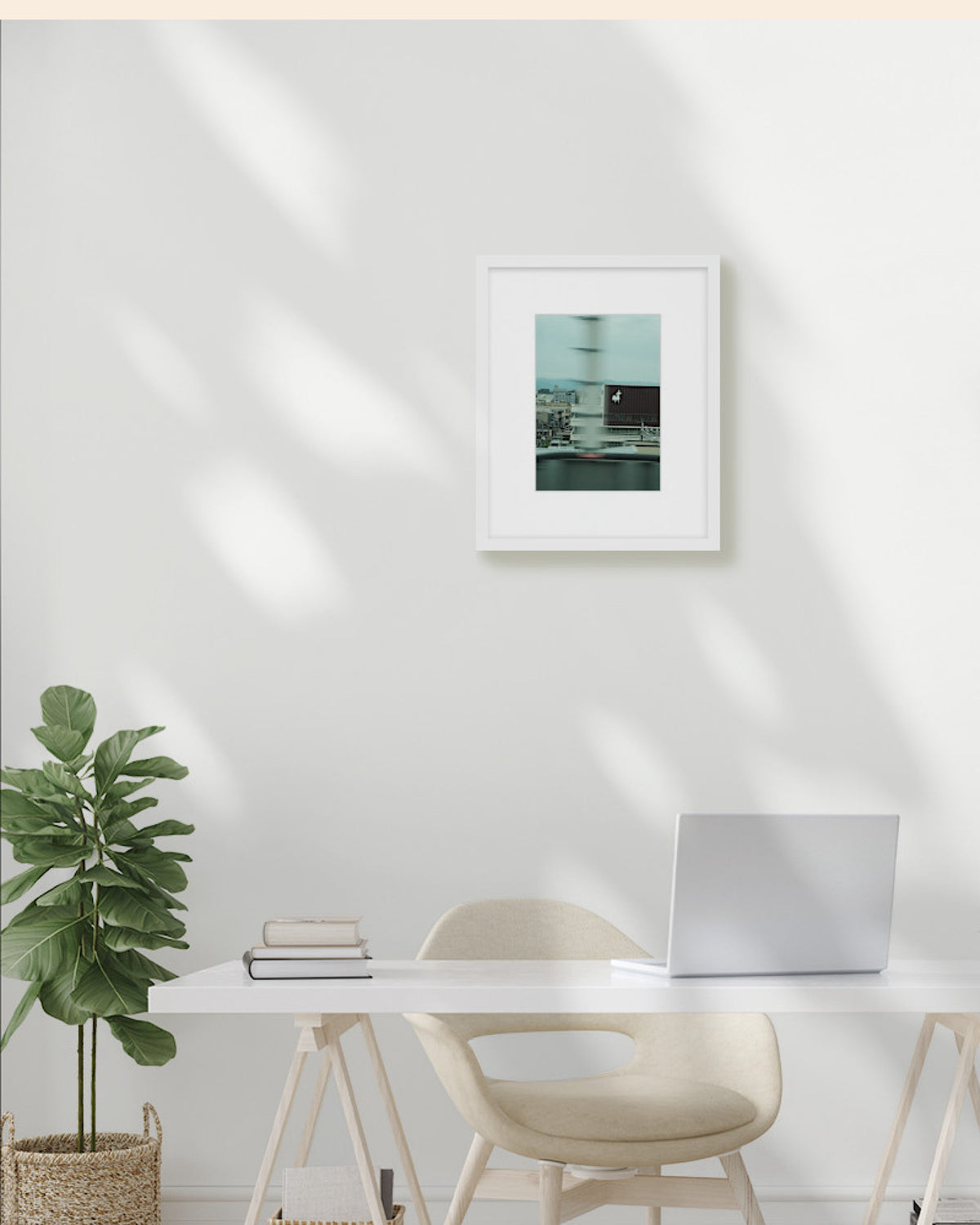 Modern office setup with a desk, chair, plant, and framed picture on a white wall.