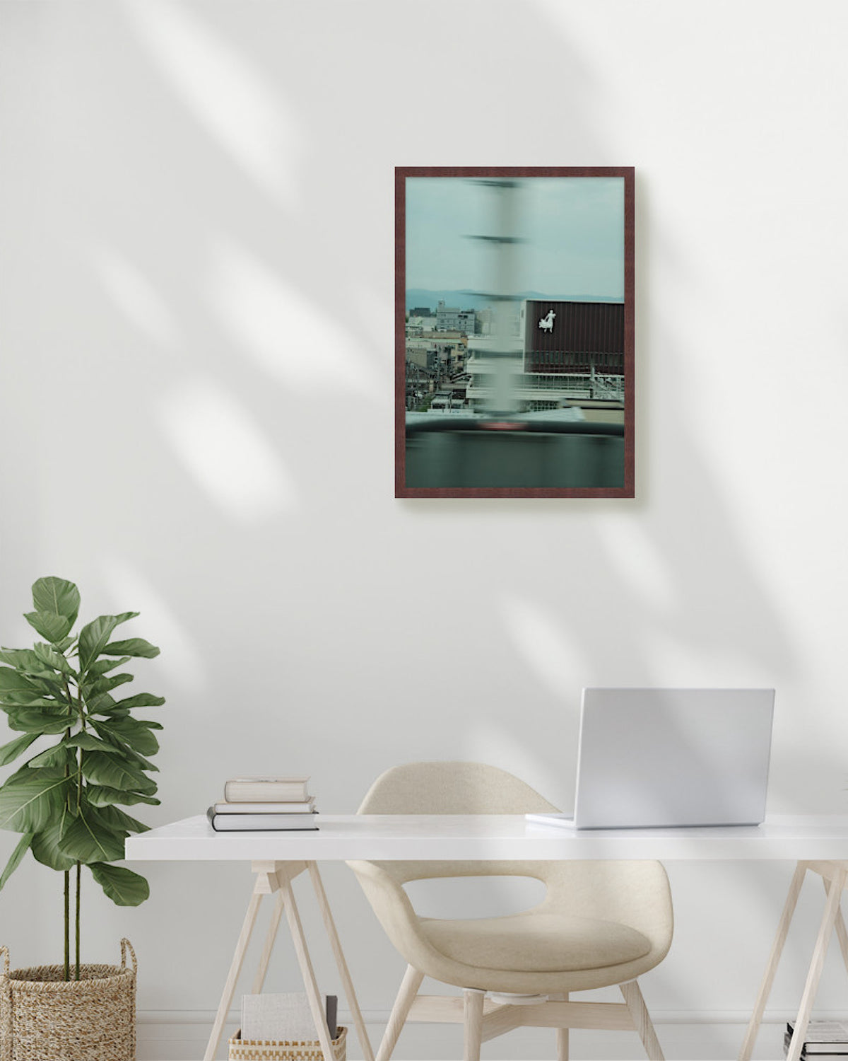 Modern office setup with a framed picture on the wall, desk, chair, and plant.