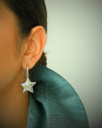 Model wears silver star earrings