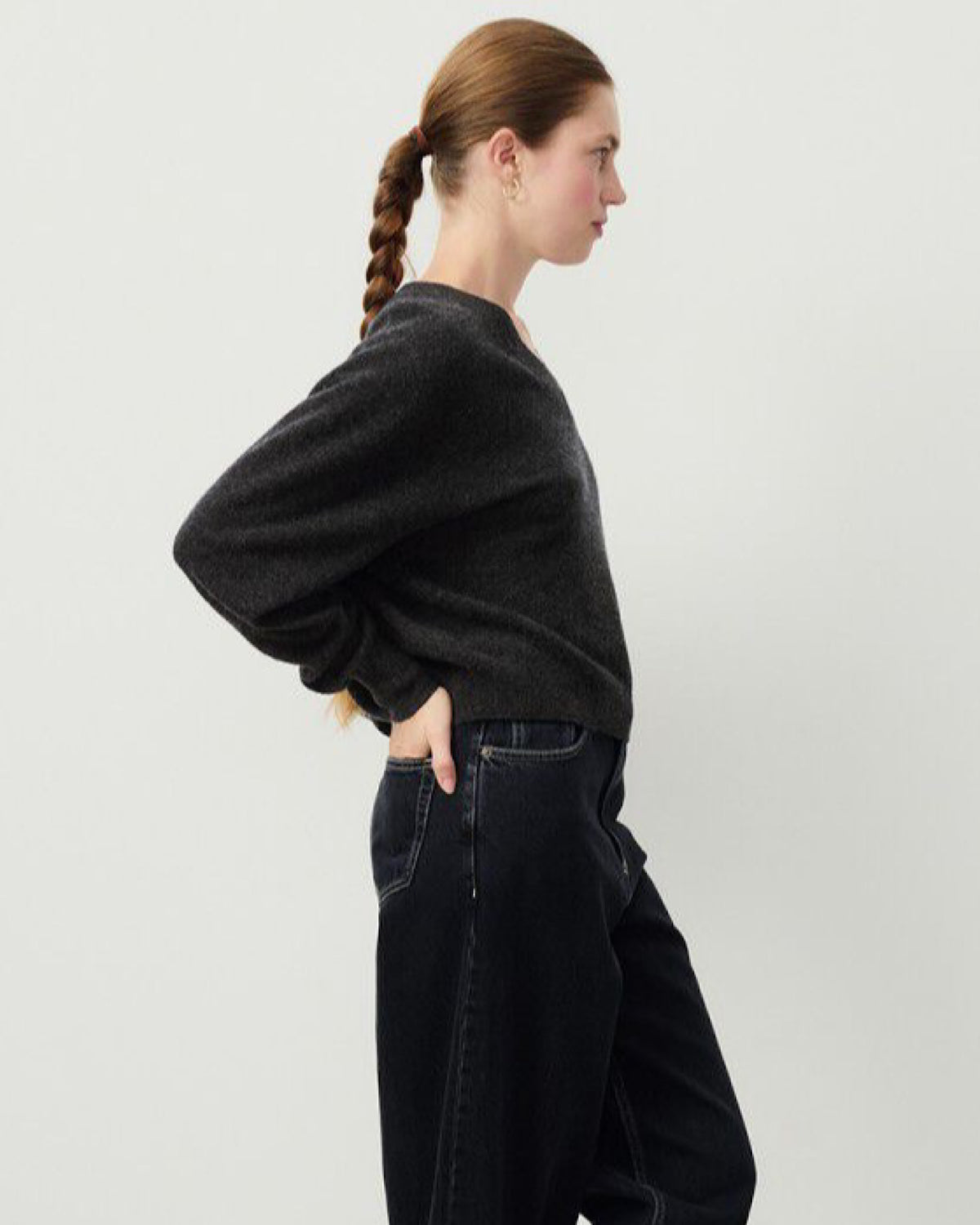Model wears a dark charcoal v neck Razow Sweater from American Vintage