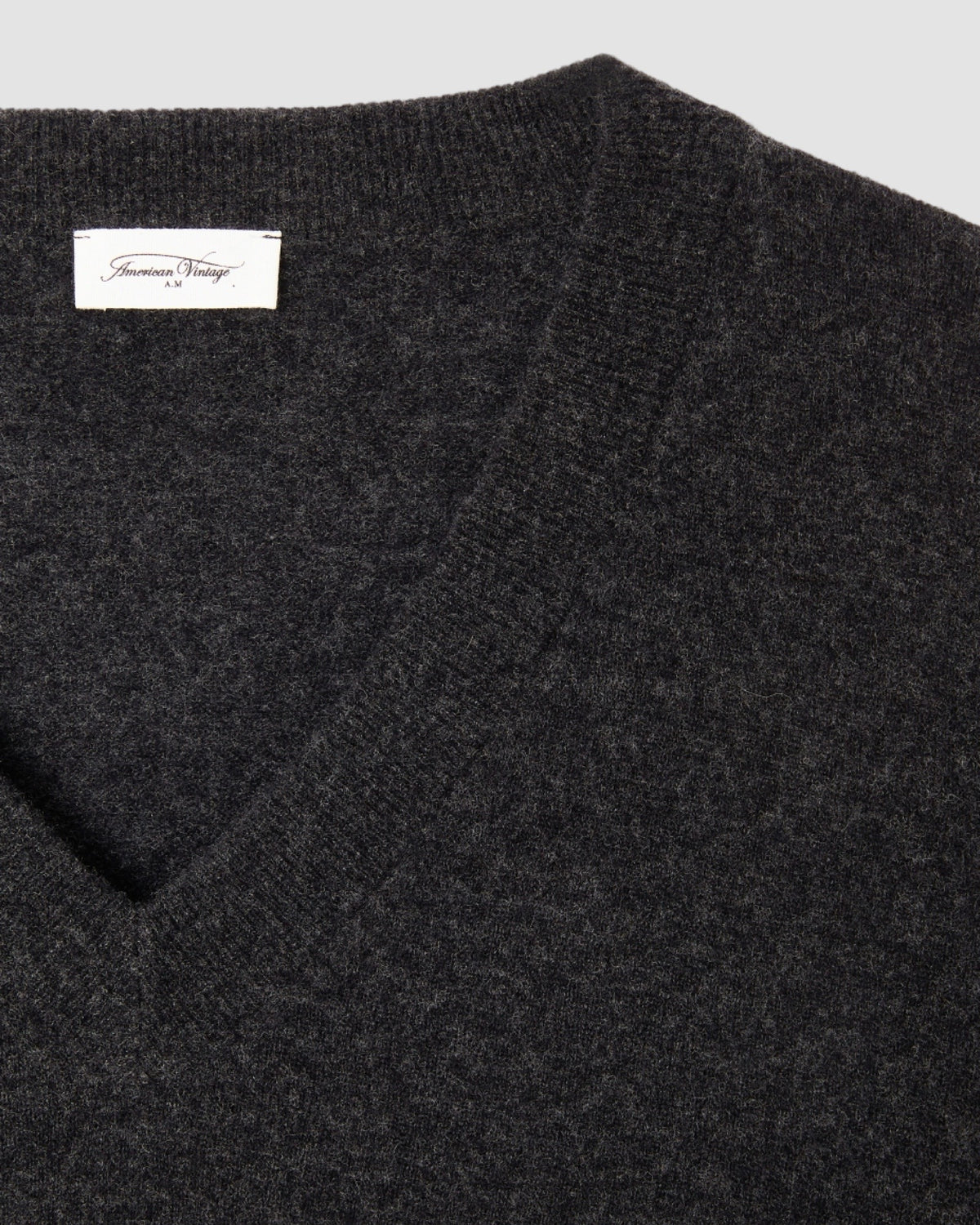 Model wears a dark charcoal v neck Razow Sweater from American Vintage