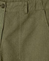 Close-up of green pants with a button and pocket detail