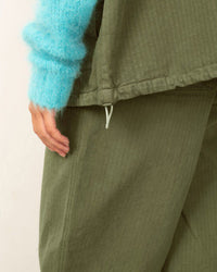 Close-up of green textured pants with a blue sleeve in the foreground