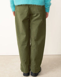 Person wearing green pants and a turquoise sweater on a plain background