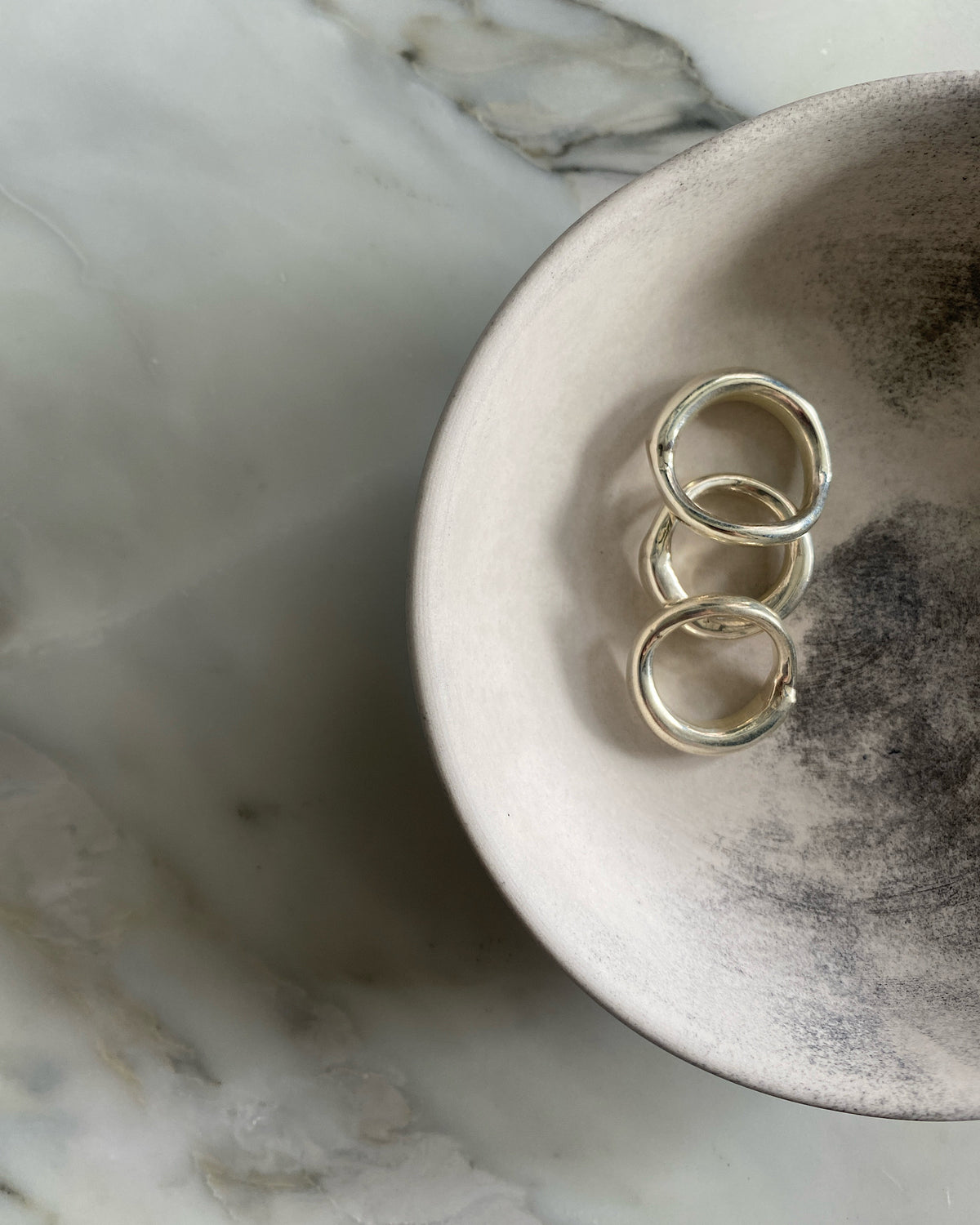 Three silver organic silver rings by Johnny Ramli sit in a bowl, Available at The Pared Store, Surry Hills