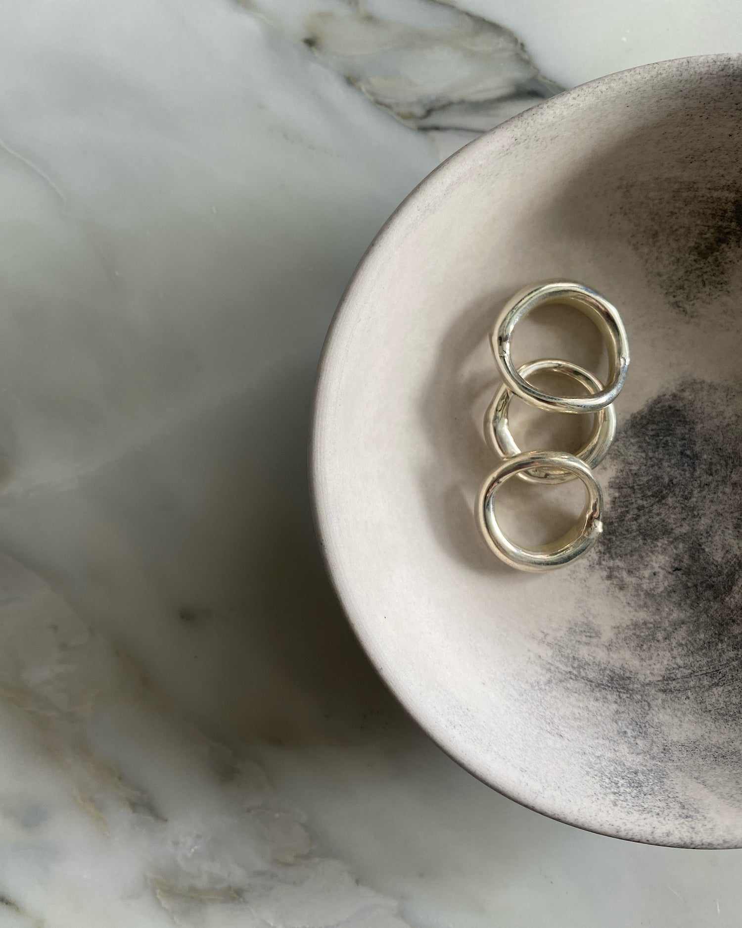 Three silver organic silver rings by Johnny Ramli sit in a bowl, Available at The Pared Store, Surry Hills