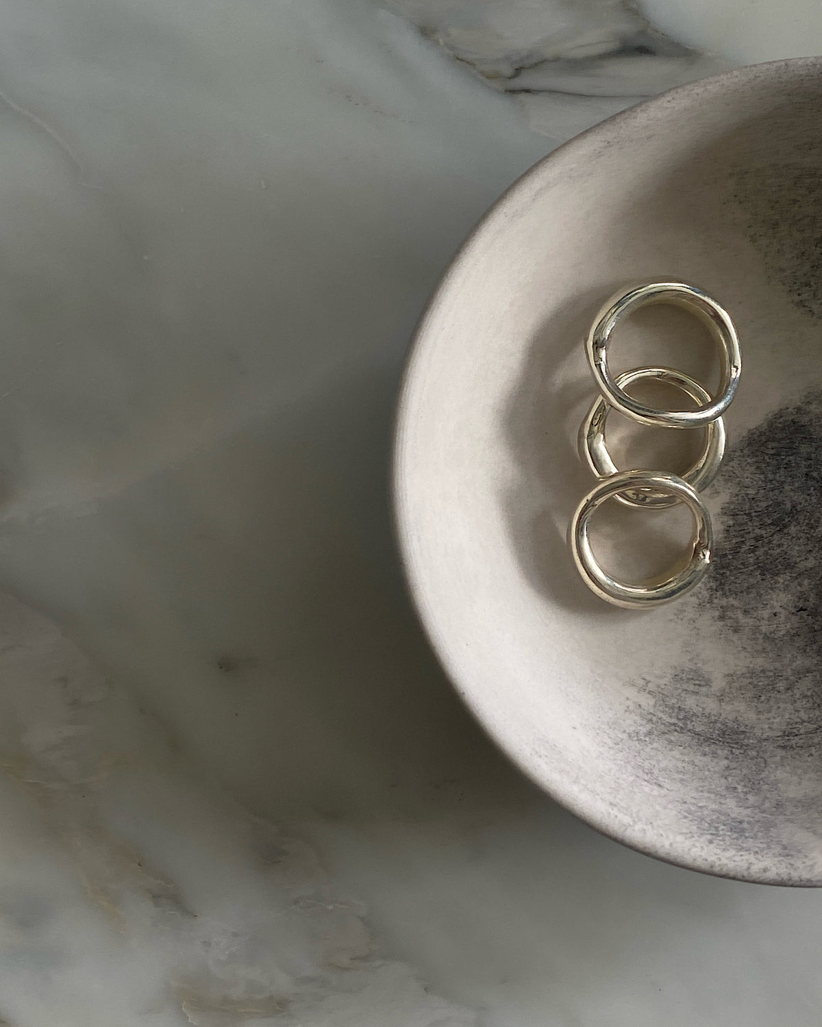 Three silver organic silver rings by Johnny Ramli sit in a bowl, Available at The Pared Store, Surry Hills