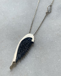 Closeup of Johnny Ramli Black Carved Wing and Silver chain Pendant available at The Pared Store