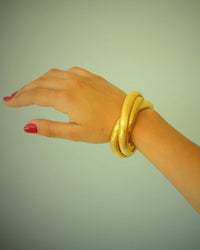 Model wears intertwinging gold bangle