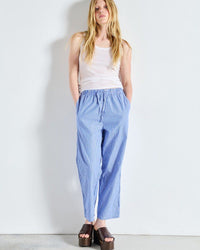 Woman wearing a white tank top and blue striped pants by American Vintage against a white background