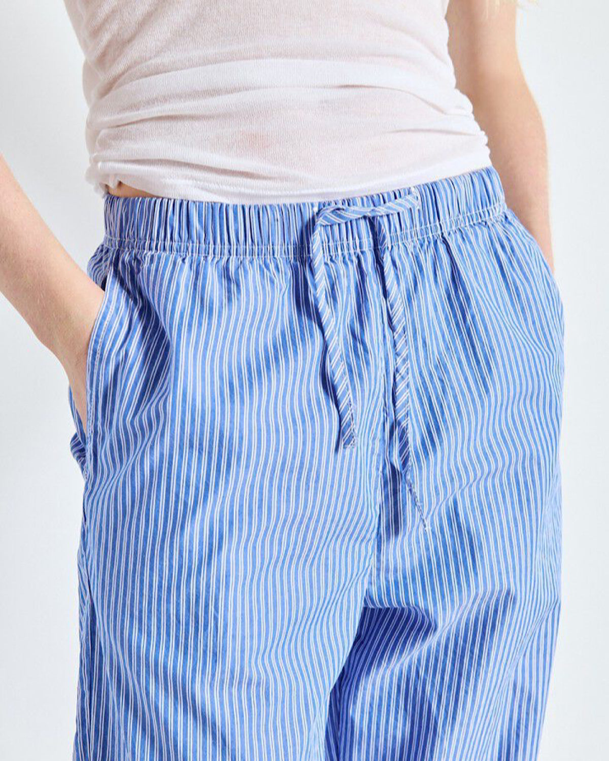 Blue striped pants worn by a person on a white background