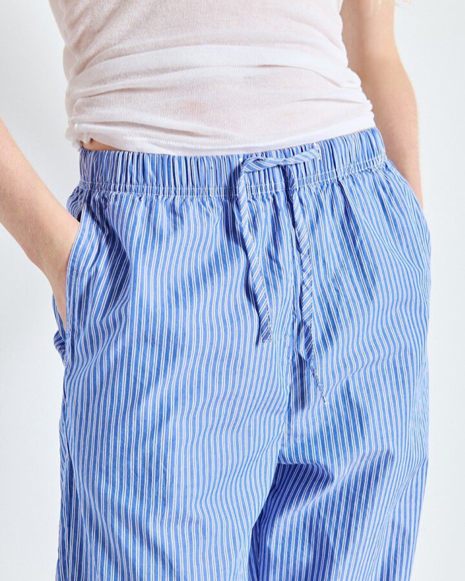 Blue striped pants worn by a person on a white background
