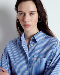 Woman wearing a blue striped shirt against a plain background