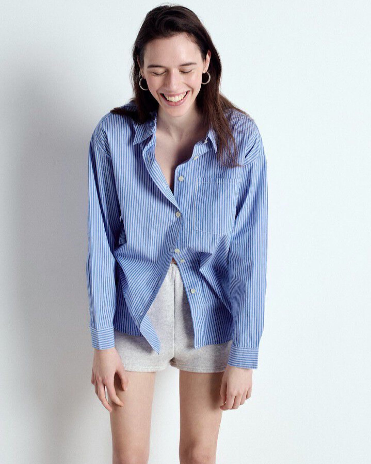 Woman wearing a blue striped shirt and shorts on from American Vinatge a white background