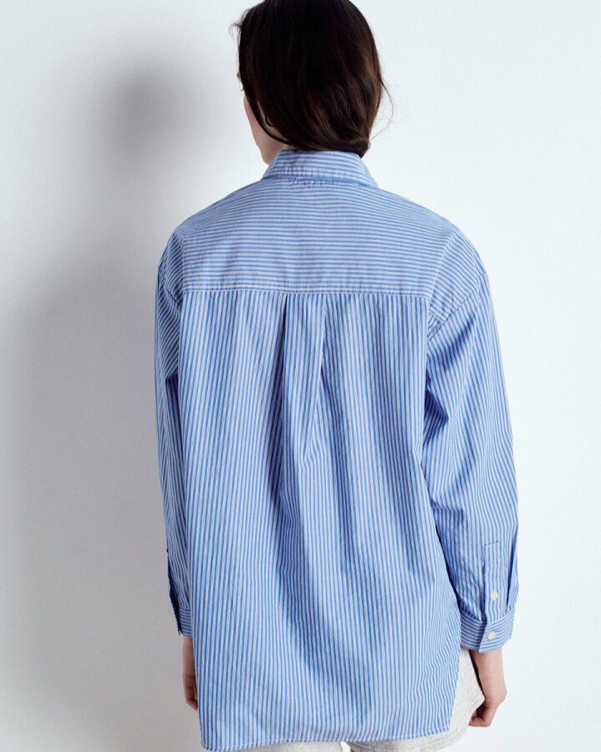Person wearing a blue and white striped shirt against a plain background