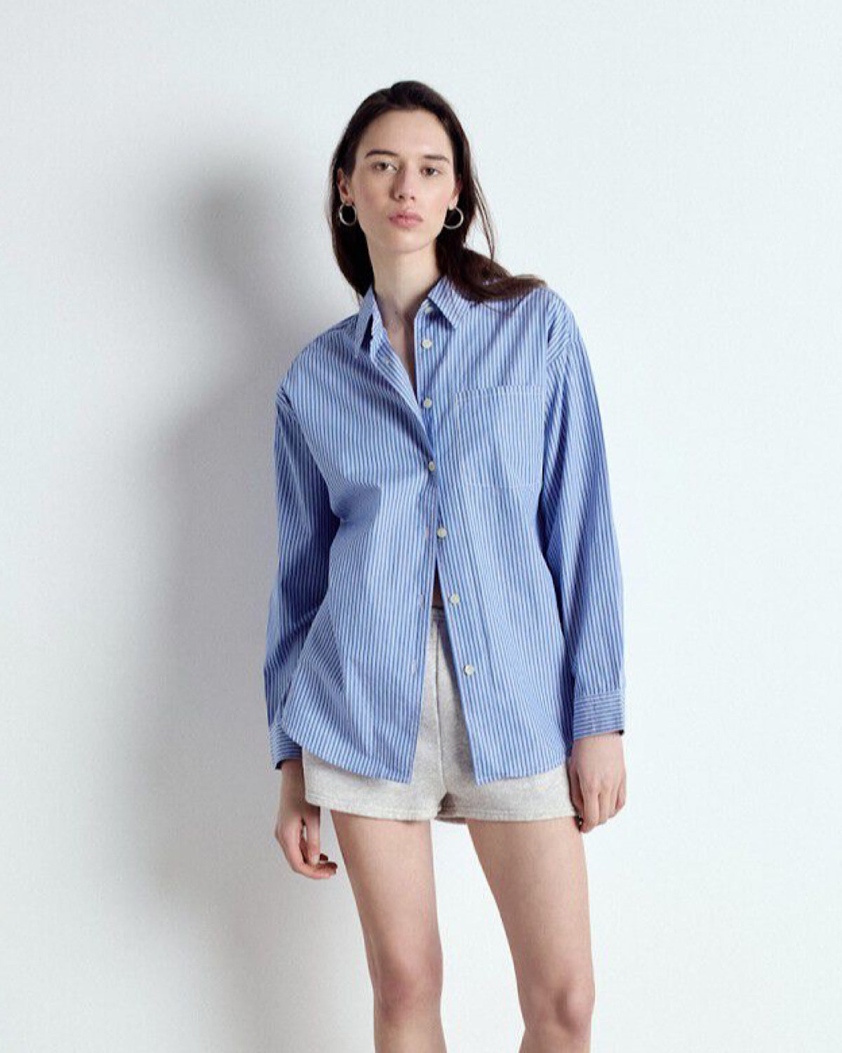 Woman wearing a blue striped shirt and shorts on a white background