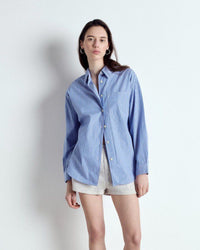 Woman wearing a blue striped shirt and shorts on a white background