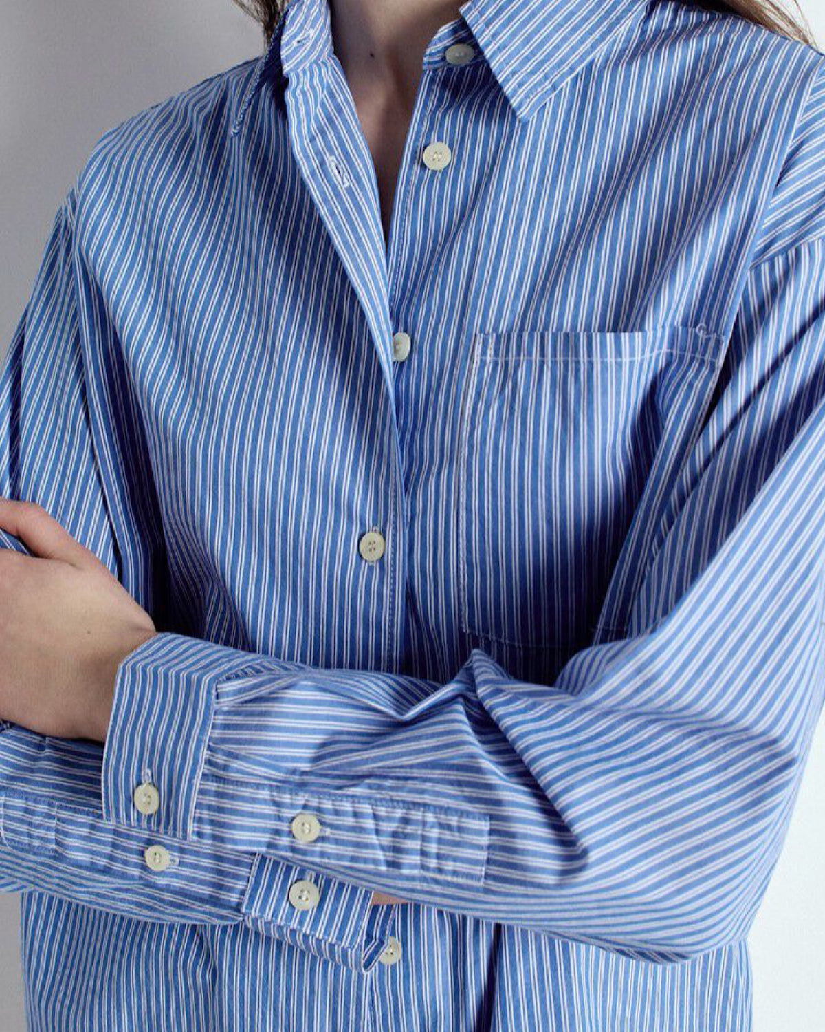 Blue and white striped shirt with a collar and buttons on a neutral background