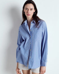 Woman wearing a blue striped shirt against a plain background