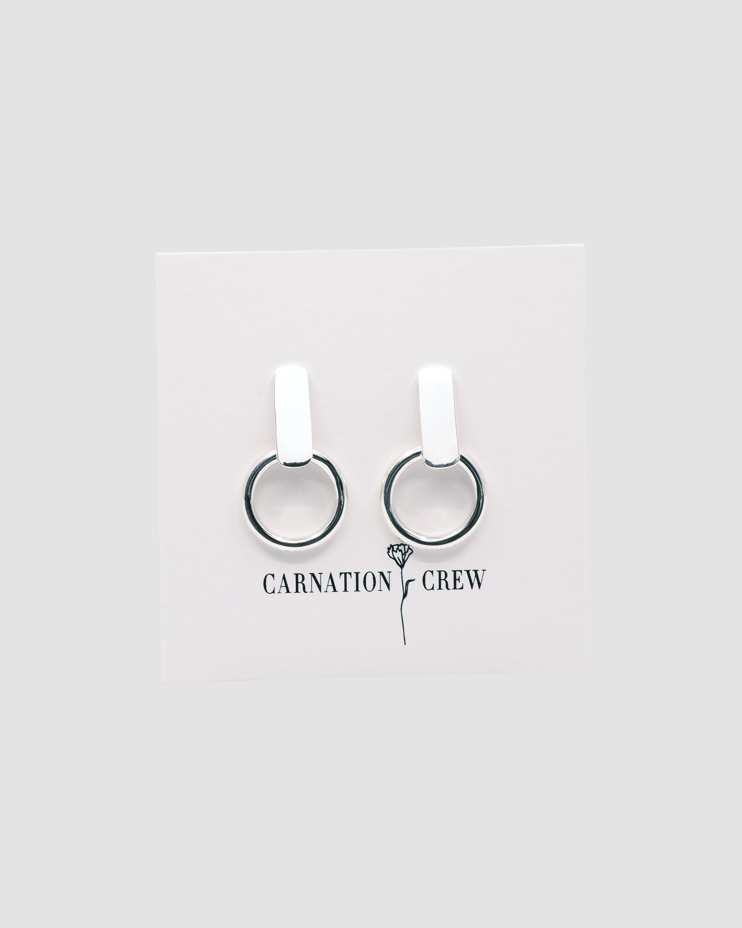 a pair of silver earrings on a card