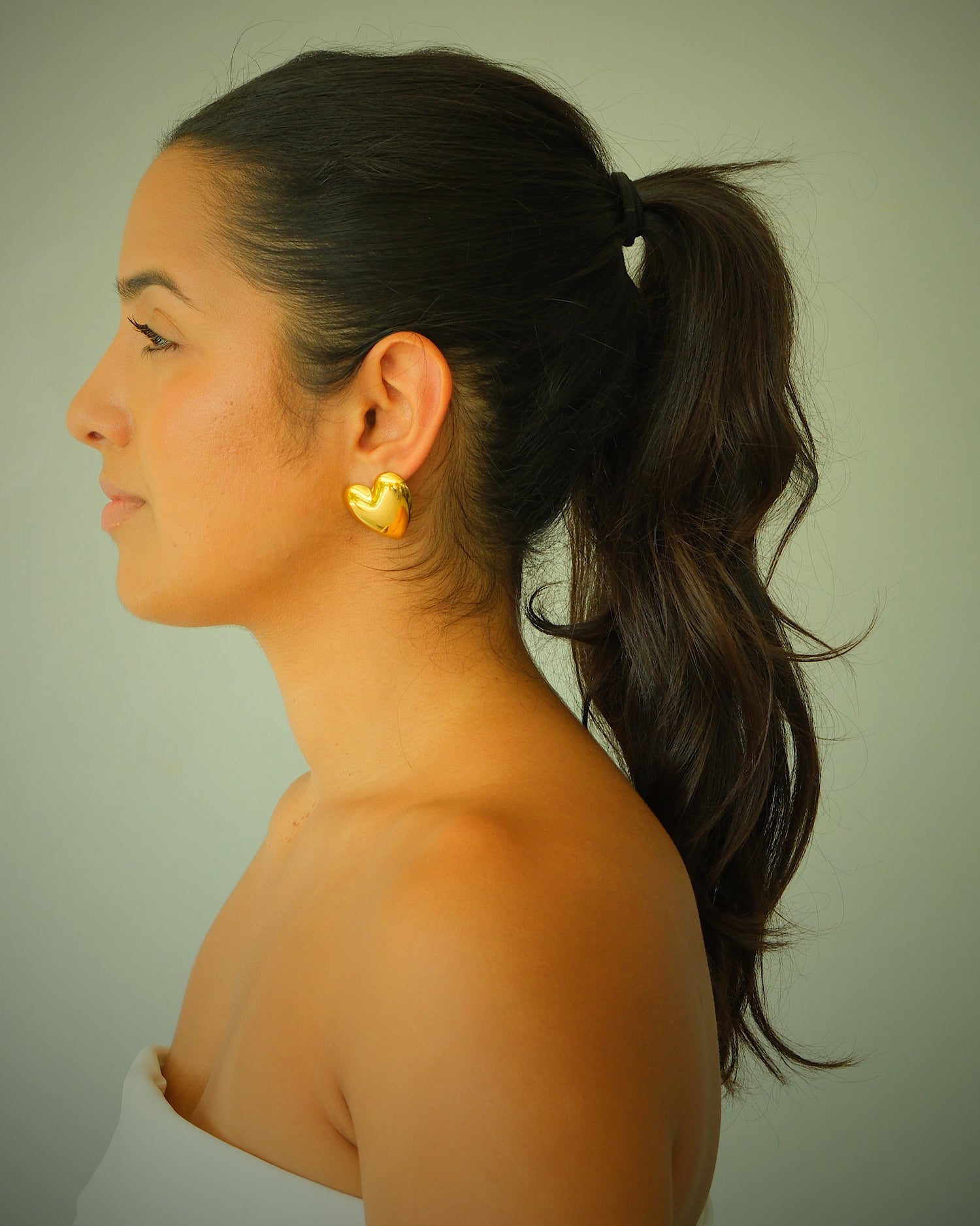 Model wears baby gold heart earrings