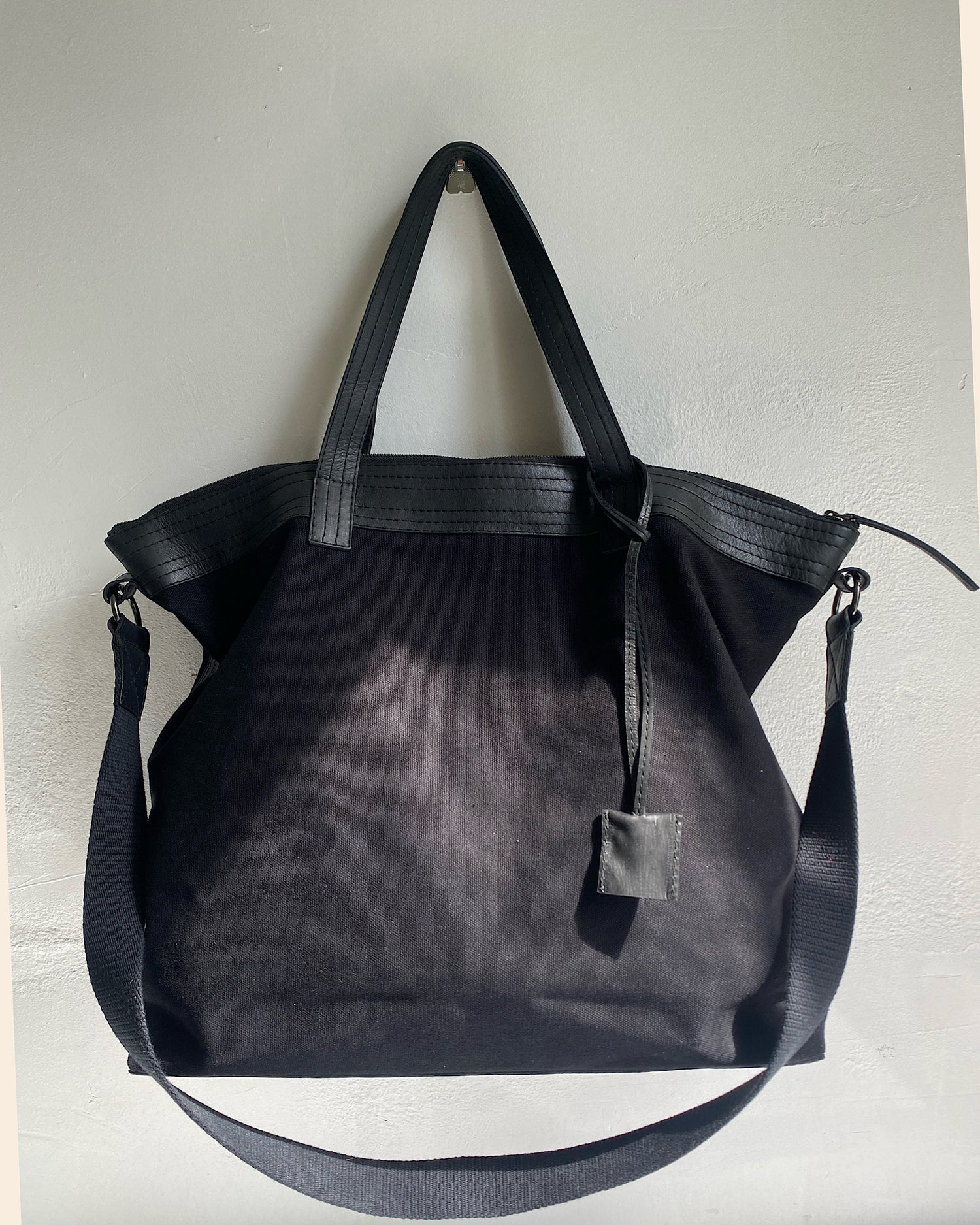 black canvas and leather overnight bag with straps on a wall