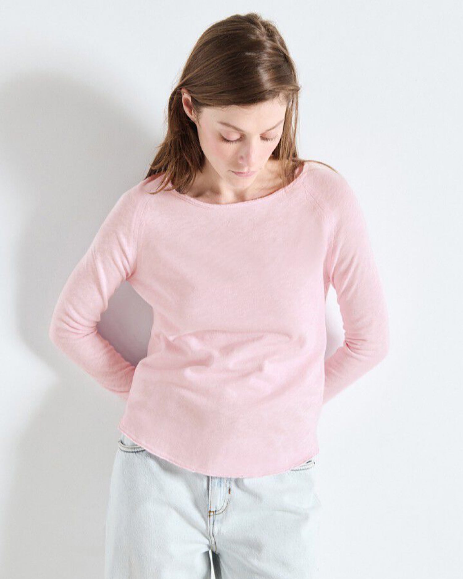 Woman wearing a pink long-sleeve top against a white background