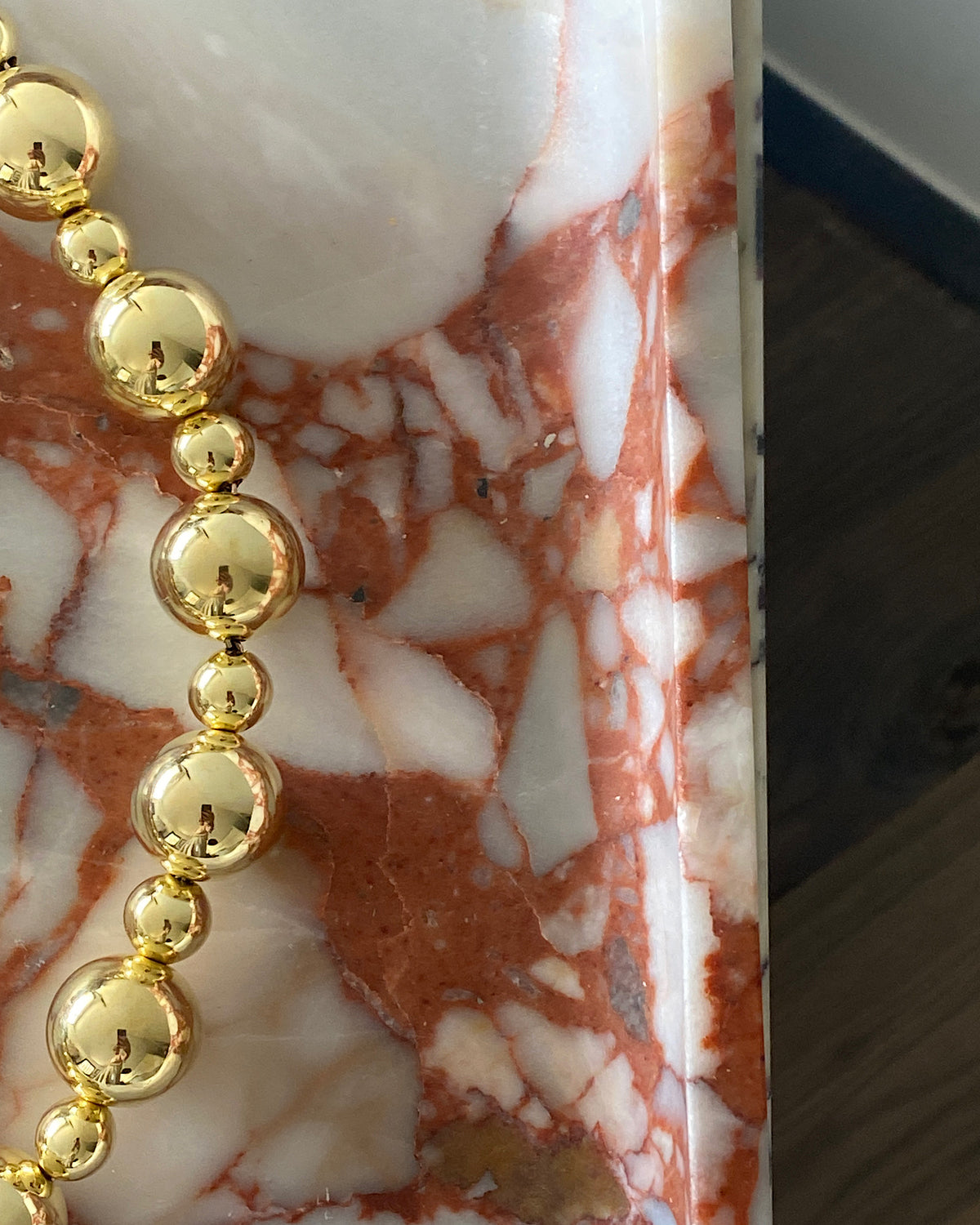 statement gold ball necklace sit on marble