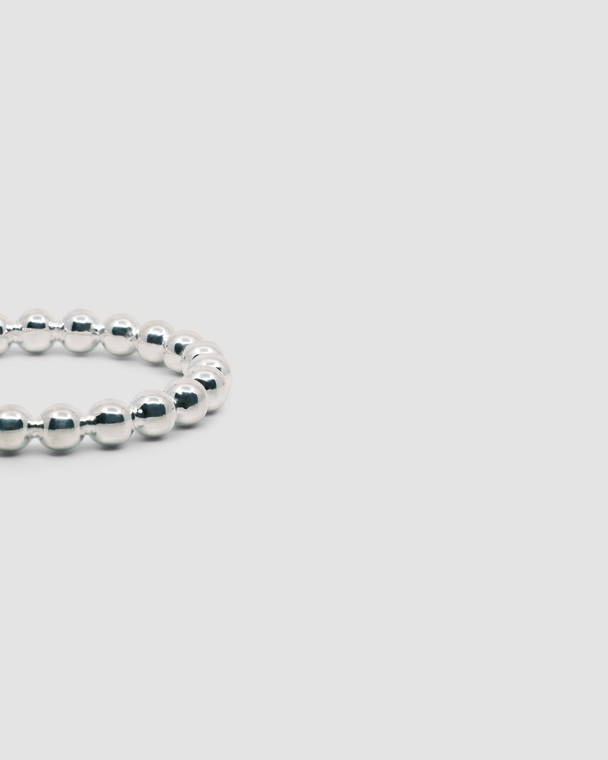 Side view of a silver ball bangle on a grey background