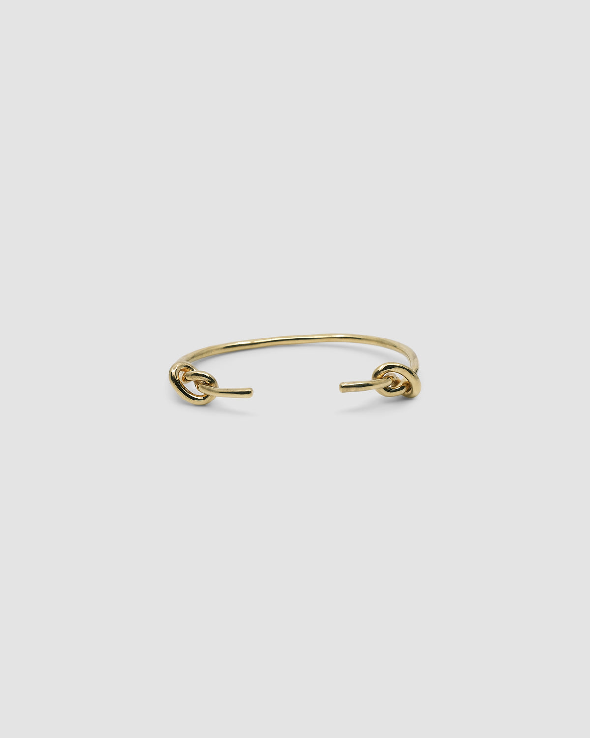 Gold open style bangle with two knots at the end